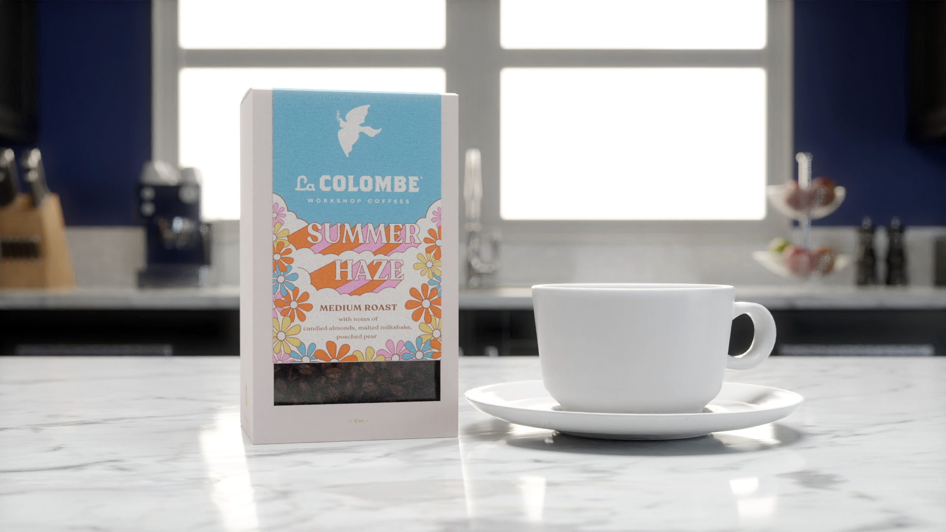 A box of La Colombe Summer Haze coffee next to a white coffee mug on a kitchen counter.